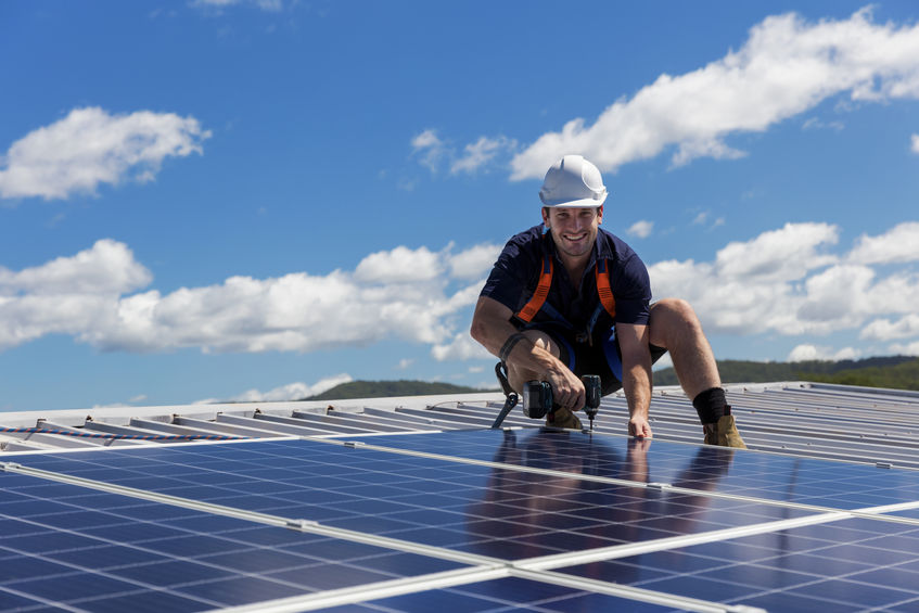 99948747 tecnico del pannello solare con il trapano che installa i pannelli solari sul tetto un giorno solegg